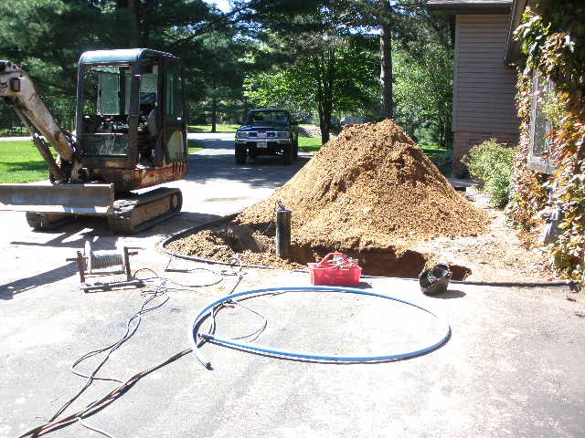 Mini excavator trenching the supply line to the home