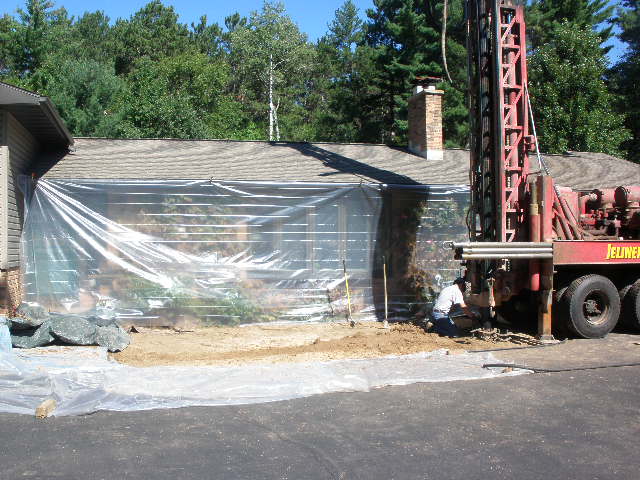 Drilling underway with plastic sheeting protecting the home